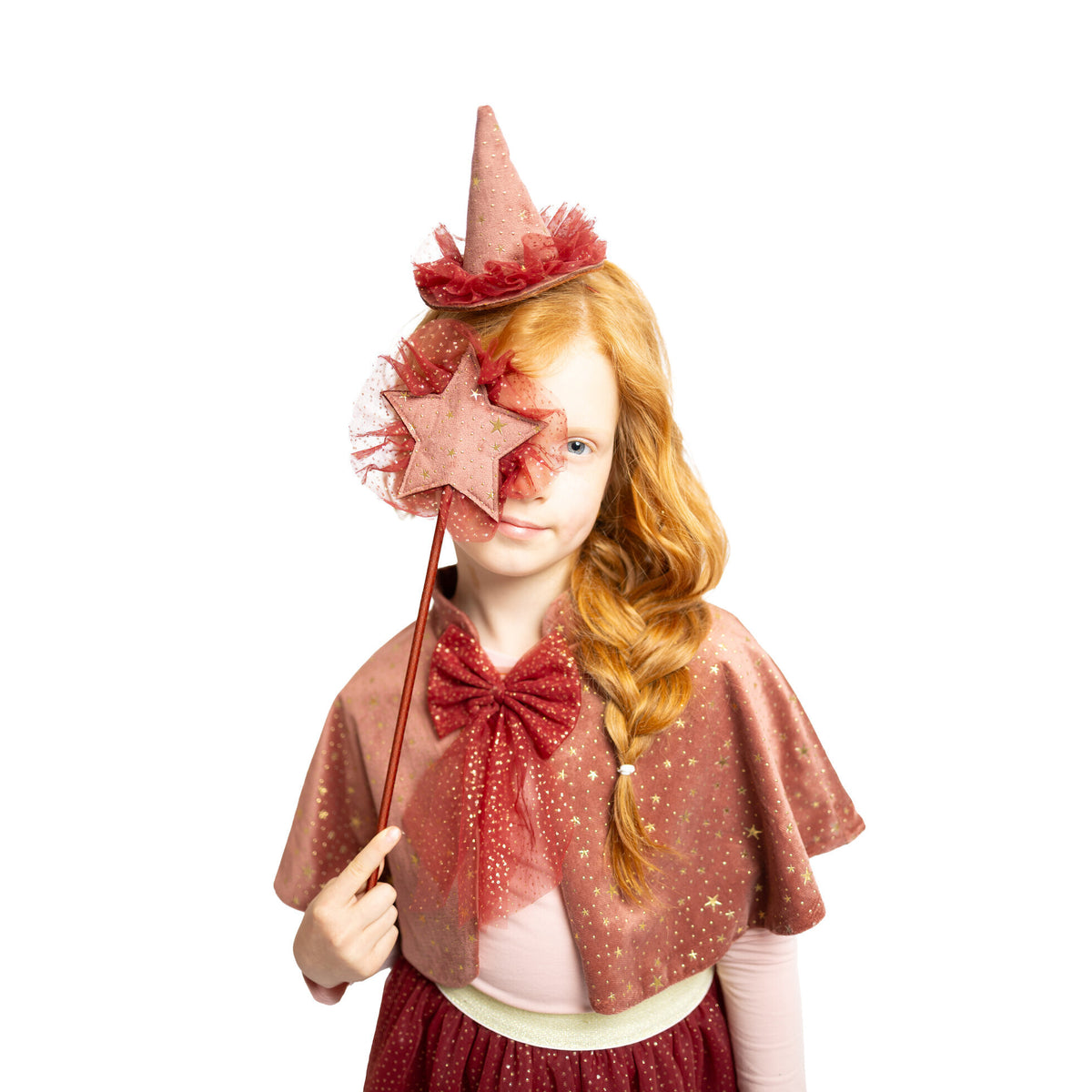 Niña con diadema de sombrero y varita del set pequeña Bruja granate; la capa no forma parte del set.