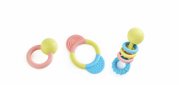 Tres sonajeros y mordedores de colores suaves con aros y piezas para agarrar.