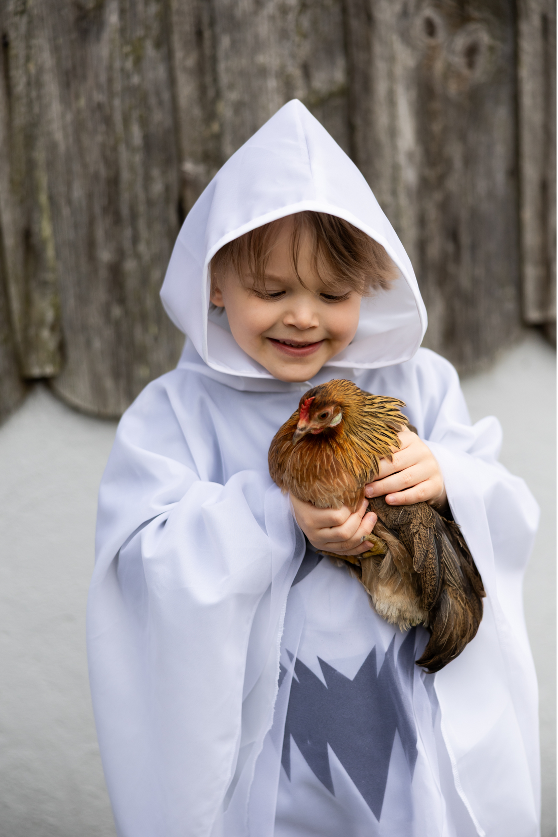 Niña pequeña con poncho blanco de fantasma con cara negra paseando por un jardín