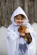 Niño con la capucha del poncho de fantasma puesta sosteniendo una gallina
